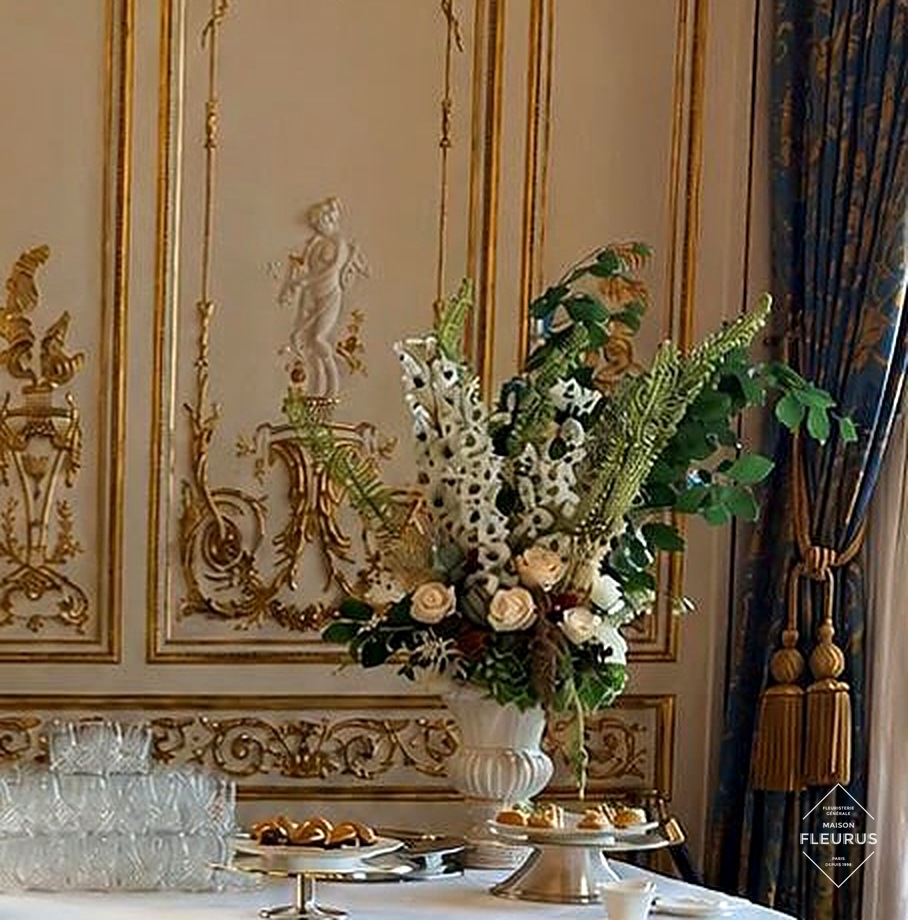 Composition florale Maison Fleurus dressée sur une table de réception, boiseries dorées